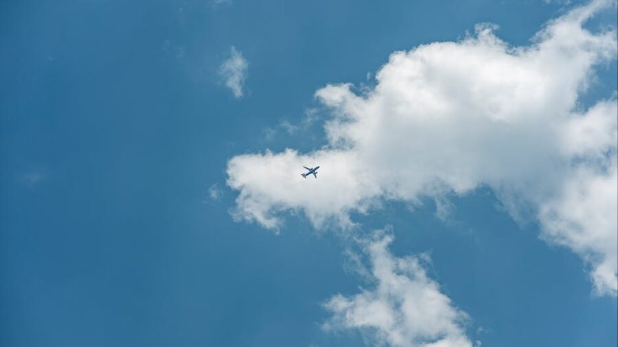 Commercial airplane flying through blue sky and clouds