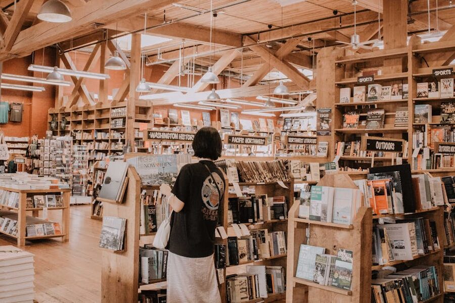 A woman browses books in a warm cozy bookstore