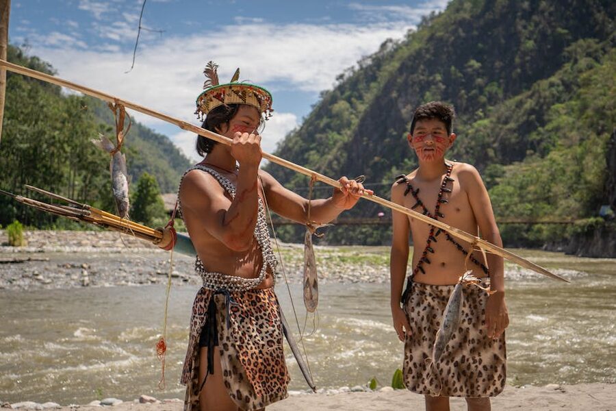 Indigenous men in traditional attire by a river in the Peruvian Amazon