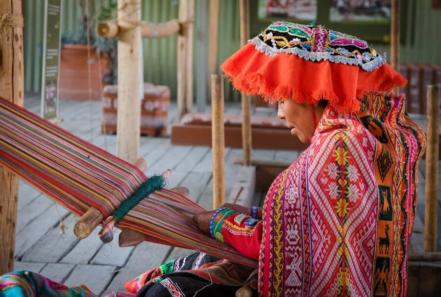A Peruvian woman weaving on a traditional loom in Cusco