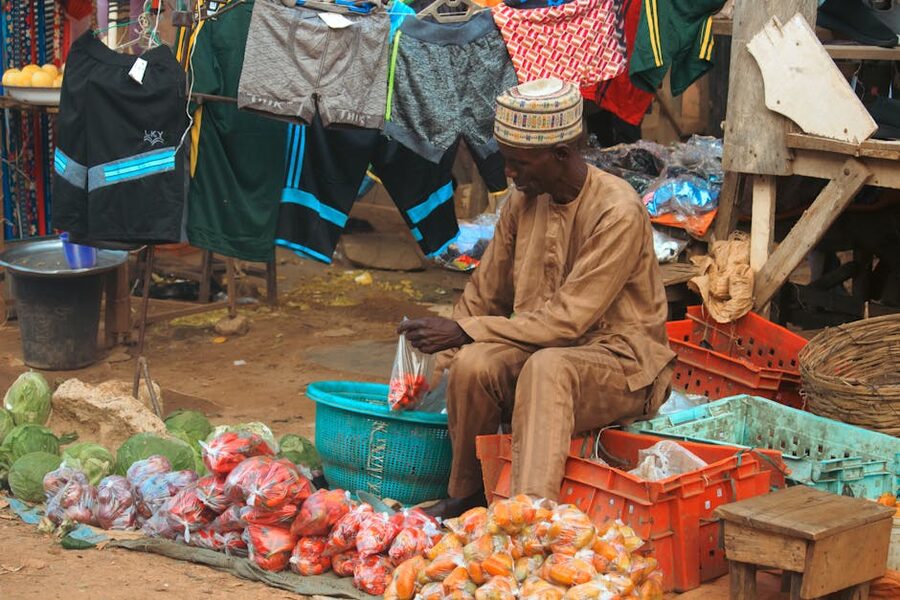 A street vendor in traditional attire arranges produce at a local market, where traveller spending stays in local hands