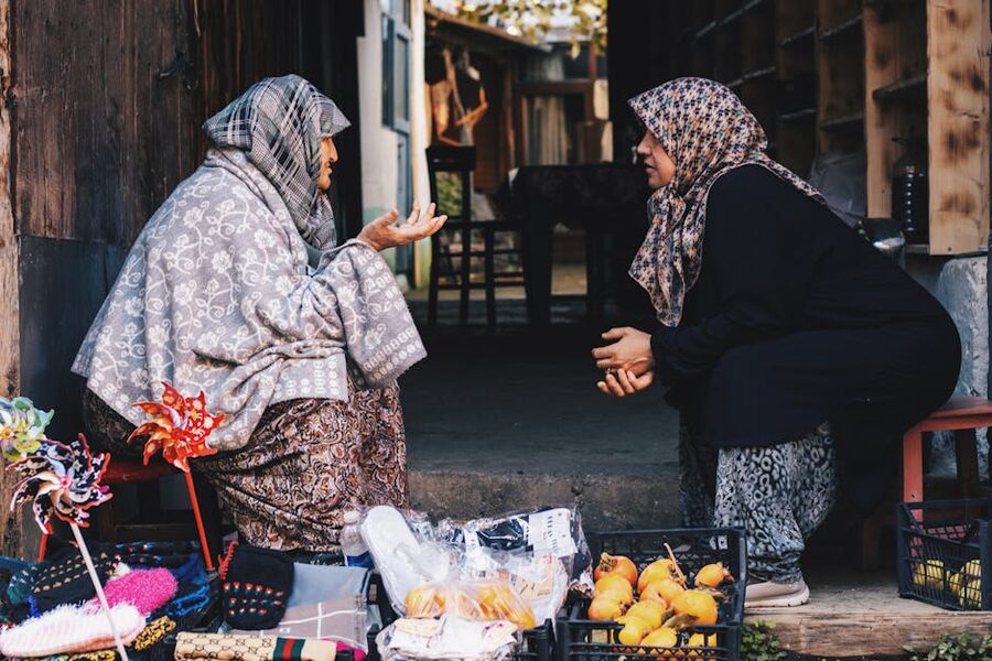 Two women in conversation at a market stall, exchanging local goods
