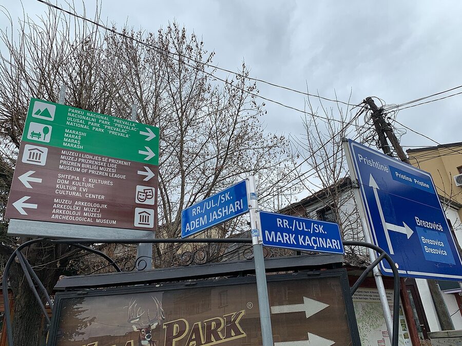 A street wall covered in multilingual signs in Prizren, Kosovo