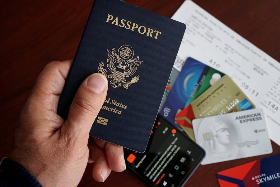 A US passport laid flat with credit cards, plane tickets and a phone