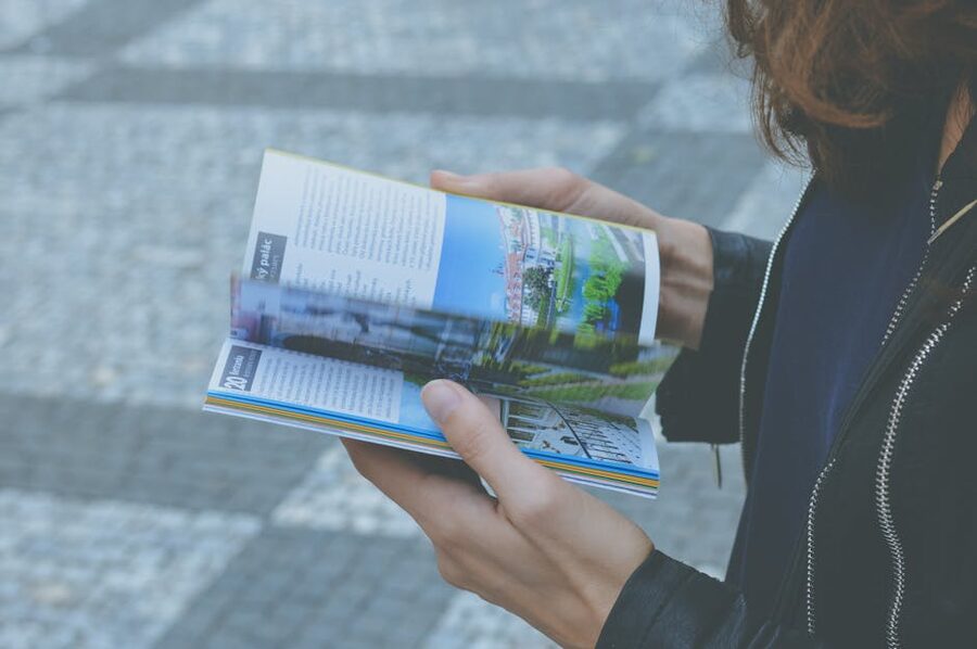 A traveller flipping through a guidebook outdoors on a sunny day