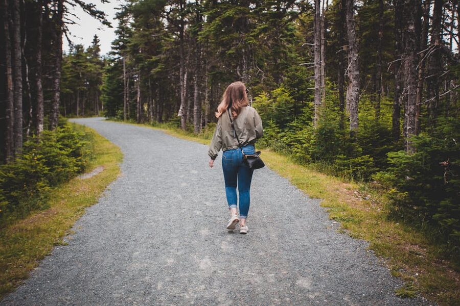 A woman walking a quiet forest path from behind