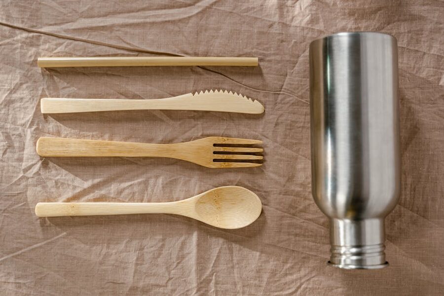 Bamboo travel cutlery laid out beside a stainless steel water bottle