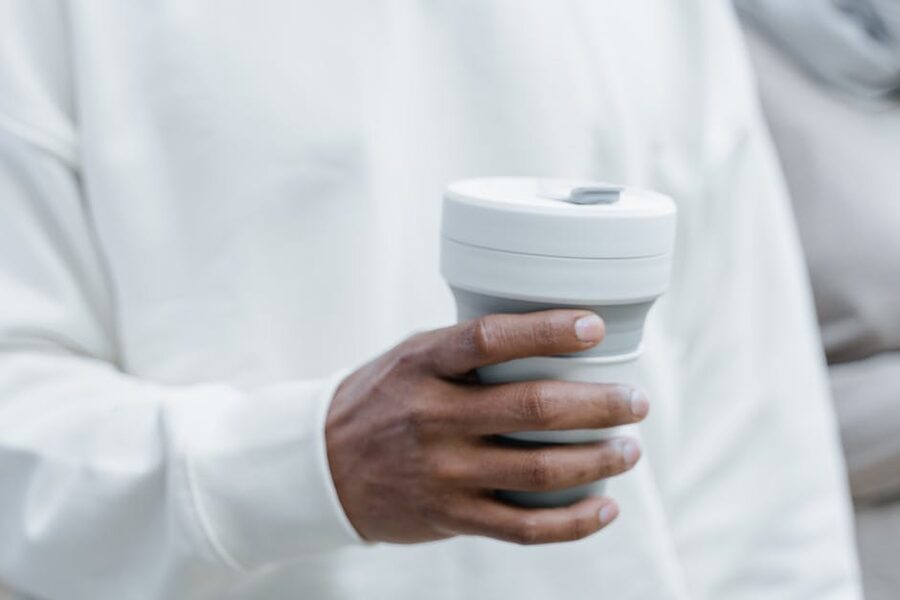 Collapsible silicone reusable coffee cup held in hand