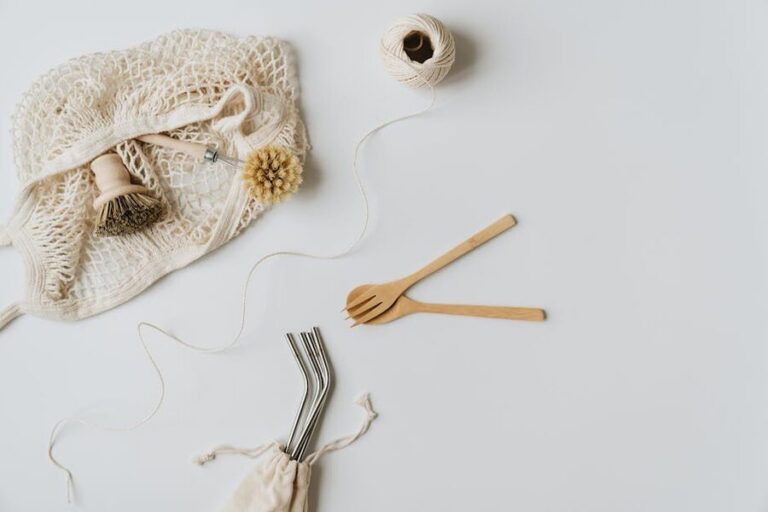 Plastic-free travel kit flat lay with bamboo cutlery, glass jar, and net bag