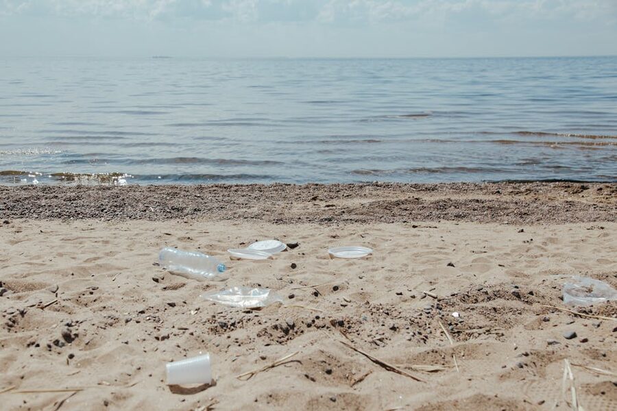 Plastic bottles and bags washed up on a sandy beach shoreline