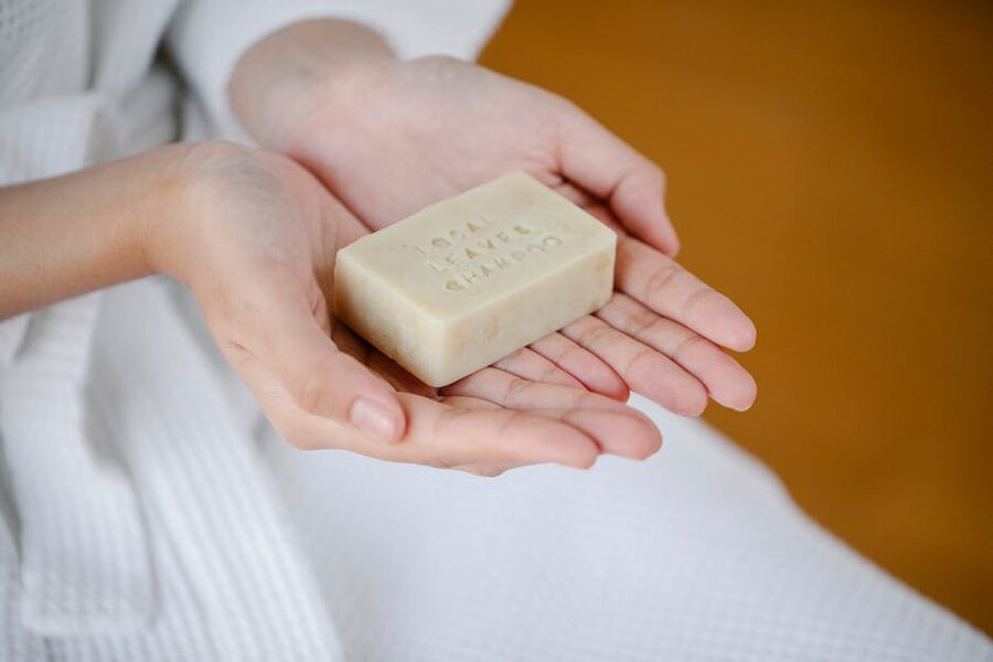 Solid shampoo bar held in hand on a tiled bathroom counter