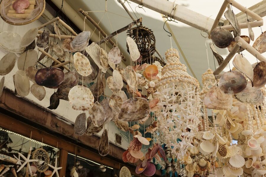 Display of seashell wind chimes hanging from the ceiling of a souvenir stall