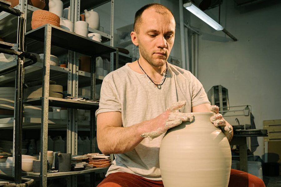 An artisan shaping a clay vase on a pottery wheel in a workshop